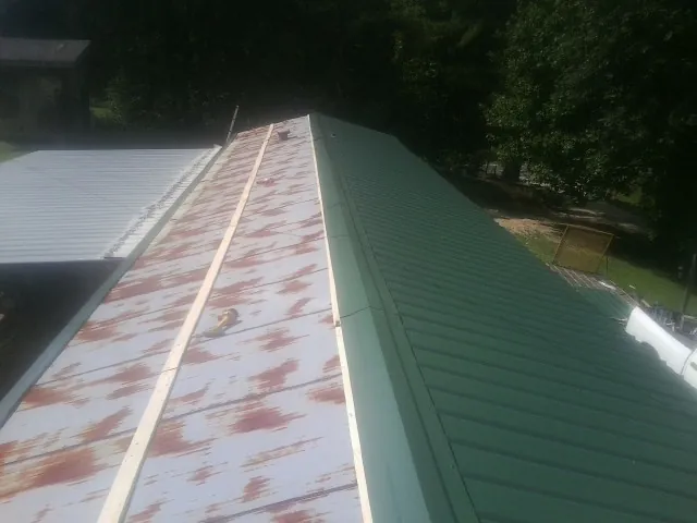 Old rusted panels beside newly installed green metal roofing — Wind Damage Roof Repair by Roofing Brothers in Saddle River
