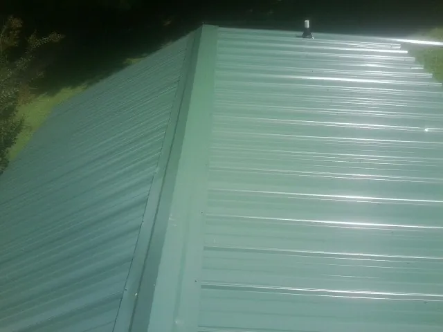 New green metal panels meeting at the ridge of a roof — Flat Roof Repair work by our crew in Saddle River
