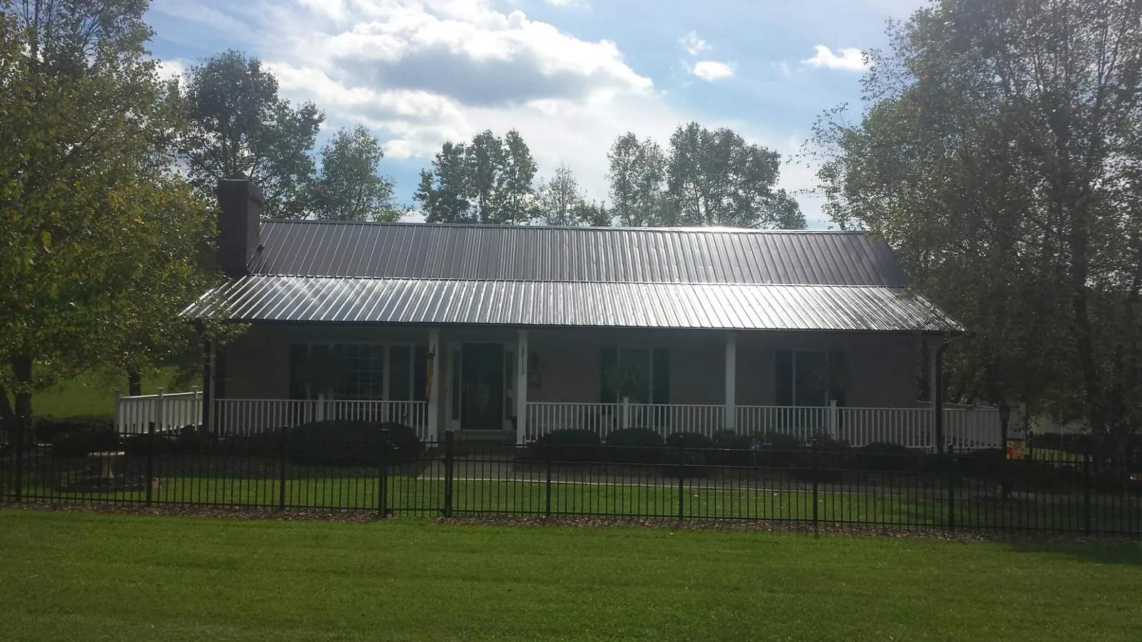 Gray metal roof on a brick ranch with a full width front porch — Gutter Guard Installation work by our crew in Saddle River