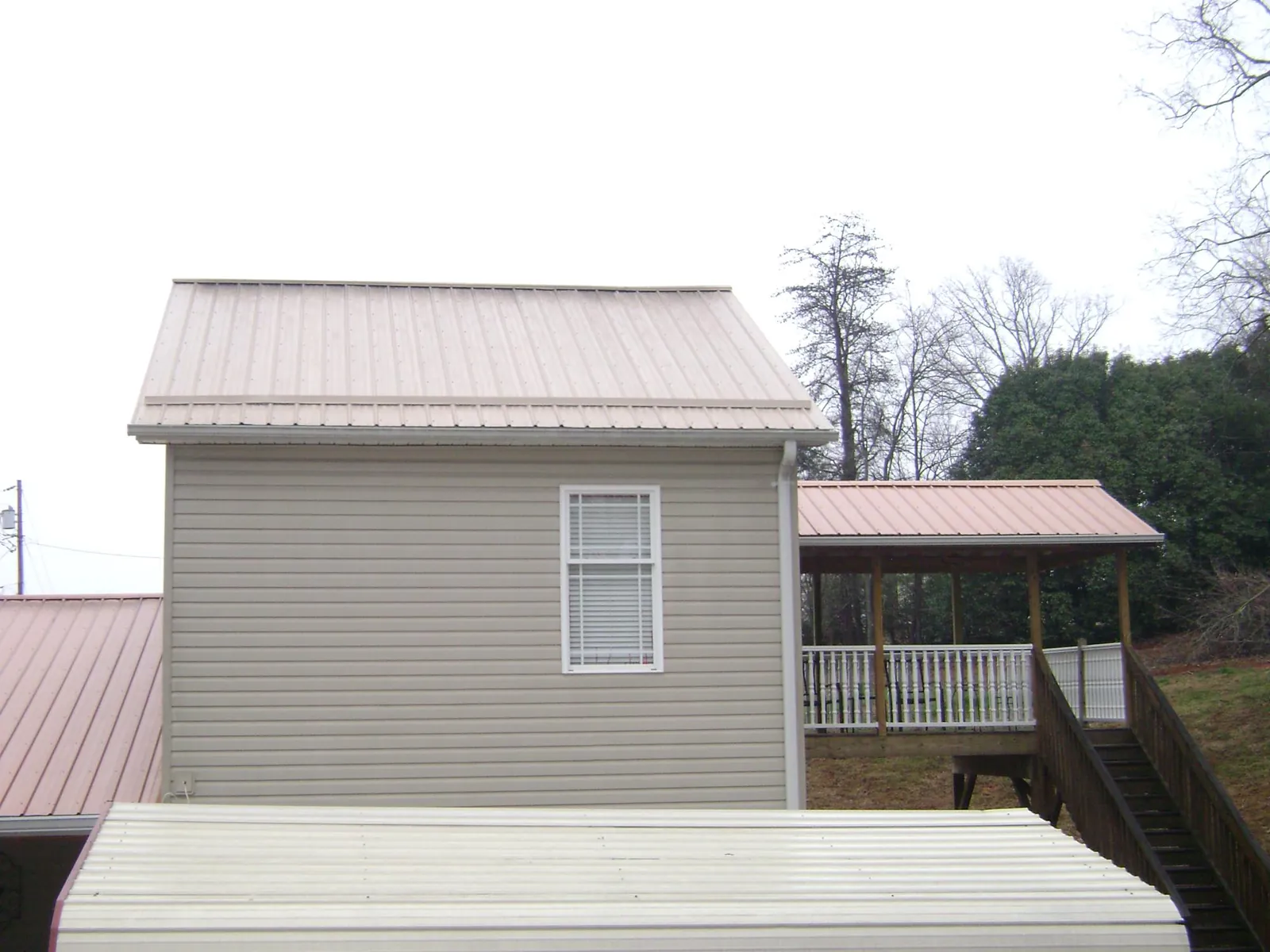 Tan metal roofs on a two story addition and attached porch, from a Roof Replacement job in Saddle River