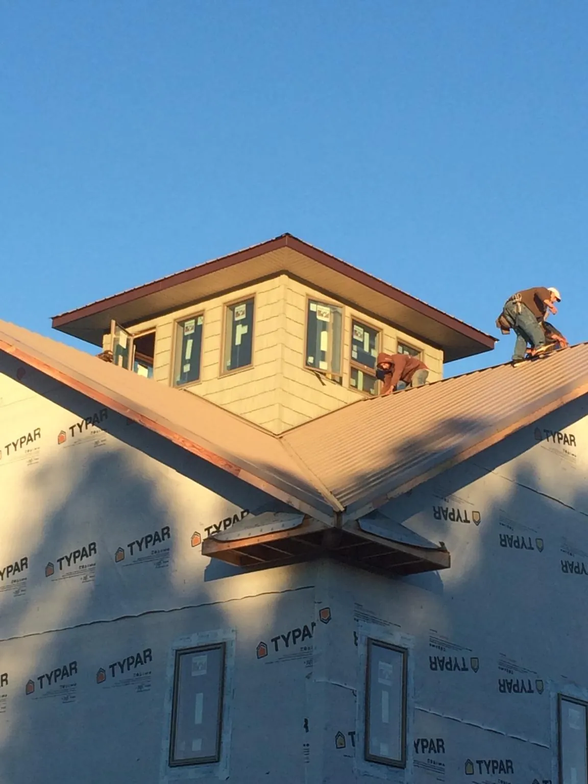 Roofers working around a rooftop cupola on a new metal roof at sunset — Roof Waterproofing in Saddle River by Roofing Brothers